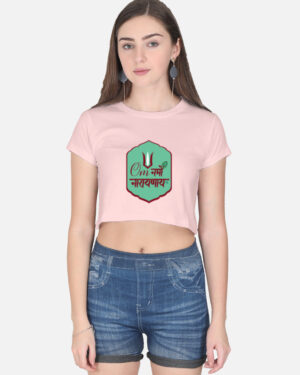 A woman wearing a light baby pink half-sleeve crop top with a green badge graphic featuring the "Om Namo Narayanaya" mantra in Devanagari script.