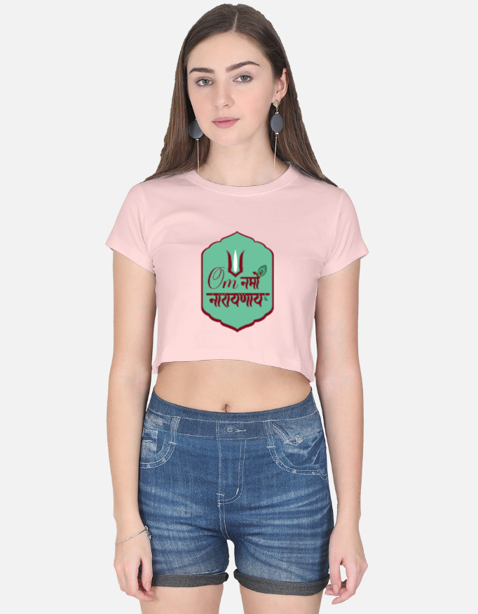 A woman wearing a light baby pink half-sleeve crop top with a green badge graphic featuring the "Om Namo Narayanaya" mantra in Devanagari script.