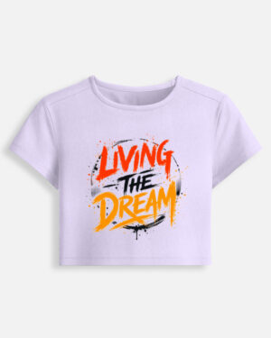 Lavender fitted baby tee featuring an energetic red, orange, and black graffiti spray typography graphic on the front that reads "Living The Dream".
