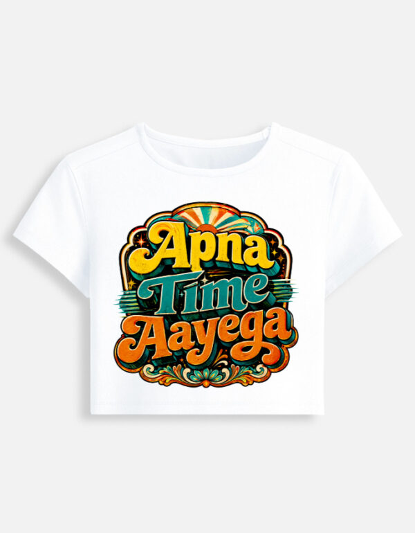 White fitted baby tee featuring a vibrant retro psychedelic typography print on the front with the phrase "Apna Time Aayega" in bold yellow, teal, and orange letters.