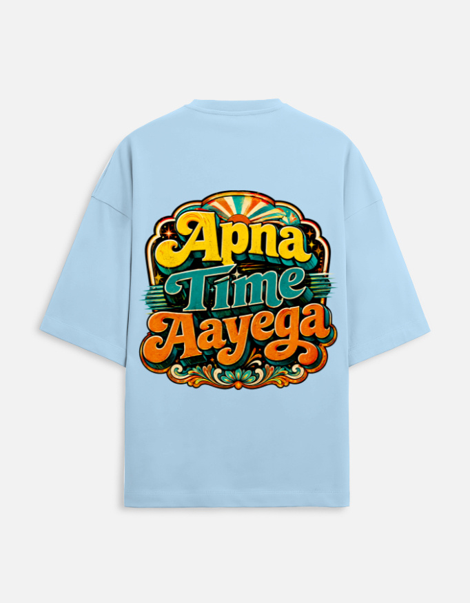 Unisex baby blue terry oversized t-shirt featuring a vibrant retro psychedelic typography print on the back with the phrase "Apna Time Aayega" in bold yellow, teal, and orange letters.