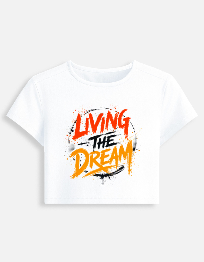 White fitted baby tee featuring an energetic red, orange, and black graffiti spray typography graphic on the front that reads "Living The Dream".