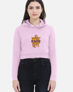 Woman wearing a light baby pink cropped hoodie featuring a yellow Devanagari script typography print with "KAOS" printed across it.