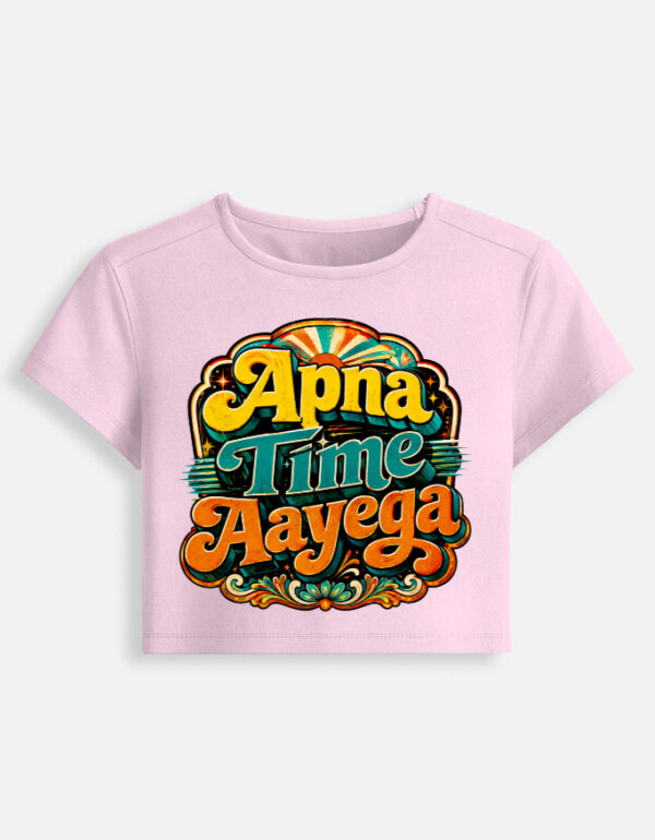 Light baby pink fitted baby tee featuring a vibrant retro psychedelic typography print on the front with the phrase "Apna Time Aayega" in bold yellow, teal, and orange letters.