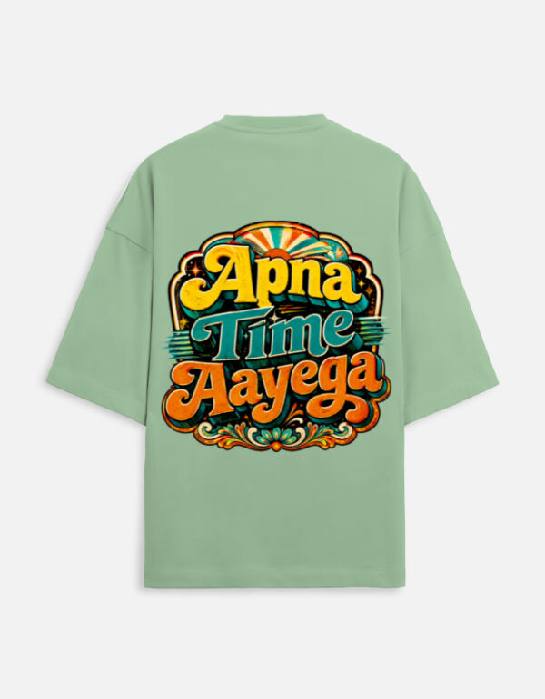 Unisex jade green terry oversized t-shirt featuring a vibrant retro psychedelic typography print on the back with the phrase "Apna Time Aayega" in bold yellow, teal, and orange letters.